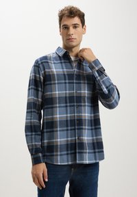 Camicia a quadri blu e grigia con colletto button-down, maniche lunghe e dettagli marroni; tessuto morbido e vestibilità rilassata.
