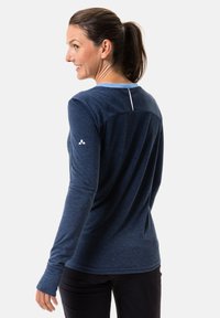Maglietta sportiva a maniche lunghe di colore blu navy con colletto blu chiaro. Presenta un tessuto testurizzato e un accento bianco sul retro. Logo sulla manica.