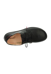 Chaussure en cuir noir à bout rond, design à lacets, texture lisse et accent rouge subtil près du talon. L'intérieur est doté d'une doublure beige.