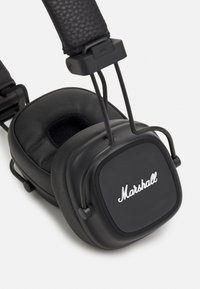 Črne slušalke čez ušesa s oblazinjenim usnjenim ušesnim podlogama, kvadratno oblikovanimi ušesnimi školjkami in srebrnim logotipom "Marshall" na sprednji strani.