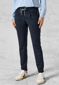Marina joggerbyxor med elastisk midja och snörning, med sidofickor och ett mjukt, stretchigt tyg. I kombination med vita sneakers.