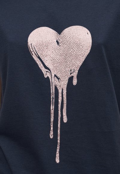 Μπλε ναυτικό βαμβακερό T-shirt με μεγάλο, γυαλιστερό ροζ καρδιά-σταγόνα που έχει εφέ στάλαξης. Η υφή φαίνεται λεία και αντανακλαστική.