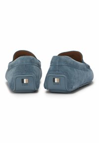Blå ruskind loafers med en glat tekstur, der har en rektangulær logoaccent på hælen og et simpelt, strømlinet design.