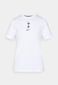 Hvid bomulds t-shirt med rund hals, prydet med et marineblåt grafisk motiv af en han på en fodbold samt et Nike-logo nedenunder.