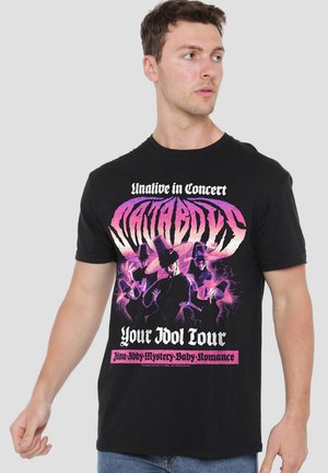 Man wearing black concert t-shirt with purple and pink graphic and text reading "Unalive in Concert, Your Idol Tour."