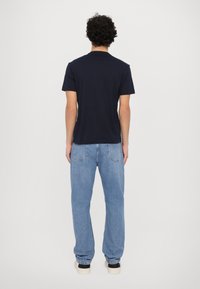 Μπλε βαμβακερό t-shirt με κοντά μανίκια, συνδυασμένο με ανοιχτό μπλε τζιν. Απλός σχεδιασμός, κανονική εφαρμογή και χωρίς ορατά λογότυπα.