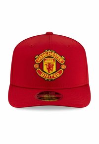 Red baseball cap featuring a prominent embroidered Manchester United logo, with yellow accents, flat brim, and structured front panel.
