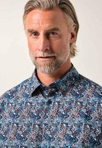 Camicia con bottoni caratterizzata da un motivo floreale blu, rosso e bianco su uno sfondo scuro. Design con colletto e tessuto dalla trama liscia.