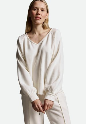 Weißer, locker sitzender Pullover mit V-Ausschnitt, langen Ballonärmeln und Bündchen. Weiches, strukturiertes Material; kombiniert mit passenden Hosen.