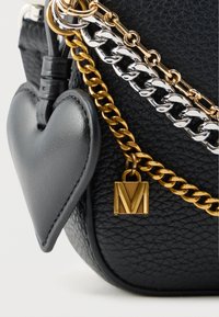 Μαύρο τσαντάκι ώμου από δέρμα με υφή, διακοσμημένο με ασημένιες και χρυσές αλυσίδες, καρδιά-σχήματος ταμπελάκι και τετράγωνο χρυσό μενταγιόν με χαραγμένο το γράμμα "M".