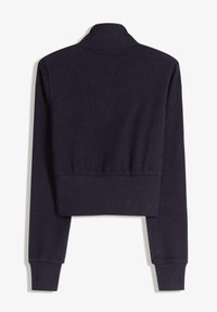 Cappotto corto a maniche lunghe di colore viola scuro con colletto alto e polsini e vita a coste, mostrato da dietro su uno sfondo bianco.