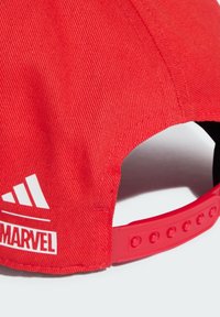 Gorra de béisbol roja con un tejido texturizado, con el logo blanco de "Marvel" y la insignia de Adidas. Correa ajustable con botones circulares en la parte posterior.