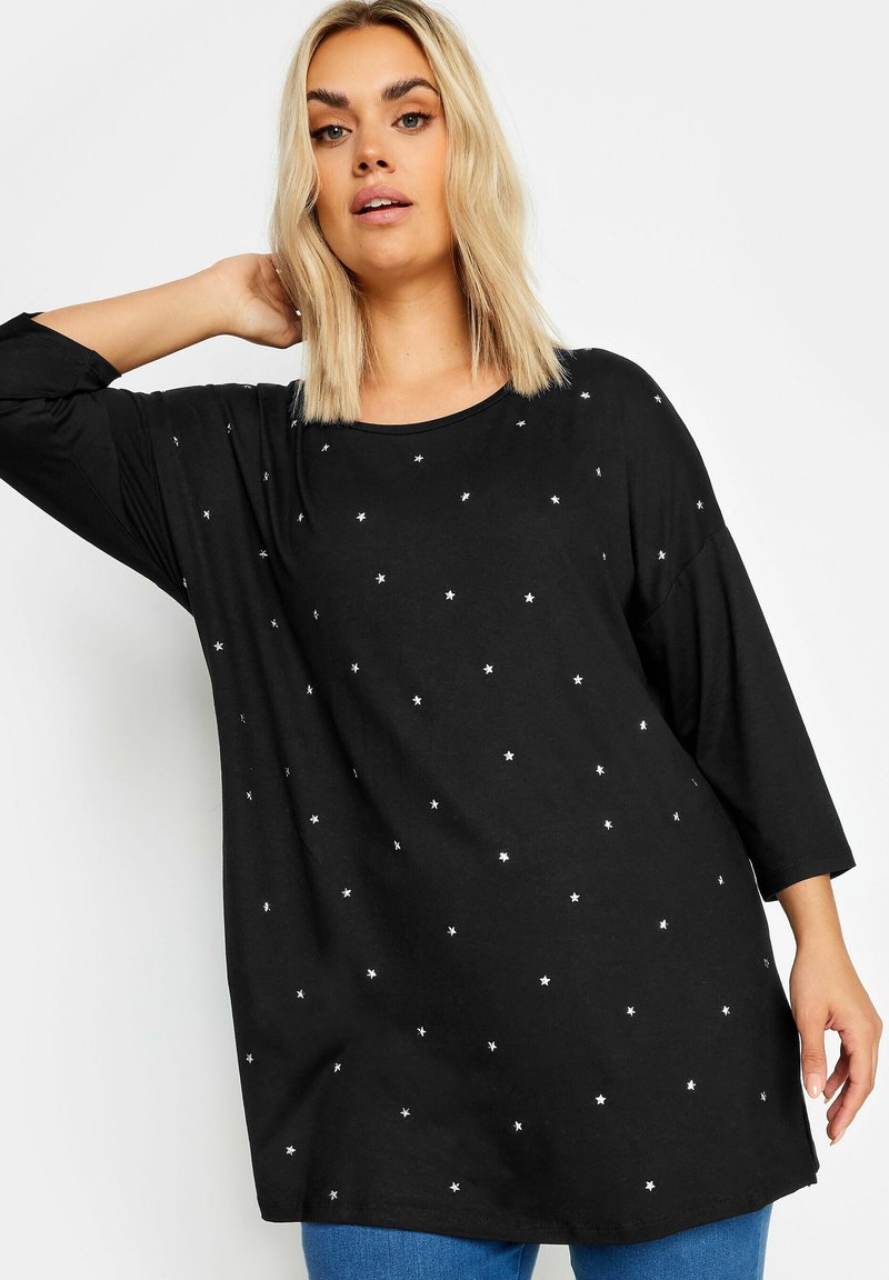 Musta pitkähihaiseksi paita pehmeästä kankaasta, jossa on hajallaan valkoisia tähtiä, pyöreä kaula-aukko ja rento, löysä malli.