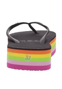 Chanclas negras con una suela de espuma gruesa y multicolor que presenta franjas horizontales en rosa, púrpura, verde, amarillo, naranja y negro. Talla 37.