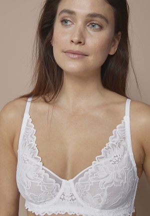 Witte kanten beha met bloemenpatroon en geschulpte randen. Heeft zachte cups en verstelbare bandjes. Lichtgewicht materiaal tegen een neutrale achtergrond.