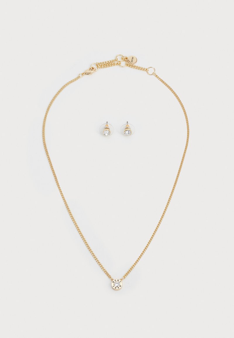 Gold chain necklace with a round pendant featuring a clear stone; matching gold stud earrings with a similar stone detail.