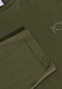 Oliwkowa koszulka z miękkiej bawełny. Krótkie rękawy z ozdobną kieszonką i kontrastującym przeszyciem. Na piersi nadruk "POL".