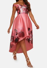 Růžové saténové šaty s květinovým potiskem; design s odhalenými rameny, asymetrický lem, přiléhavý korzet a jemná struktura s lesklým povrchem.