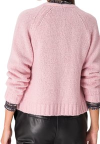 Rosa stickad tröja med ribbad nederkant och överdimensionerade ärmar, med en strukturerad väv och en något kortare design bak. 