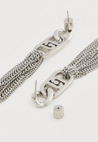 Ασημί μεταλλικά σκουλαρίκια αλυσίδας με πολλαπλές σειράδες, ορθογώνιους συνδέσμους με κομμένα νούμερα και πίσω κούμπωμα πεταλούδας σε λευκή επιφάνεια.