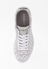Sneaker bianca con una tomaia a motivo geometrico, soletta grigia, cinque fori per i lacci e un logo sulla linguetta. Design testurizzato in tutto.