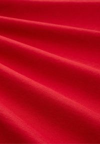 Roter Stoff mit sanften Falten, die diagonale Schatten und Highlights auf der Oberfläche erzeugen.