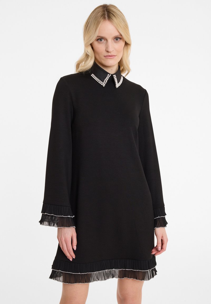 Robe noire à manches longues, col orné de perles, et poignets et ourlet texturés et plissés. Matière lisse avec une silhouette simple.
