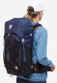 Sac à dos au design bleu et noir, fabriqué en tissu durable. Dispose de bretelles réglables, d'un détail de logo et de plusieurs points d'attache.