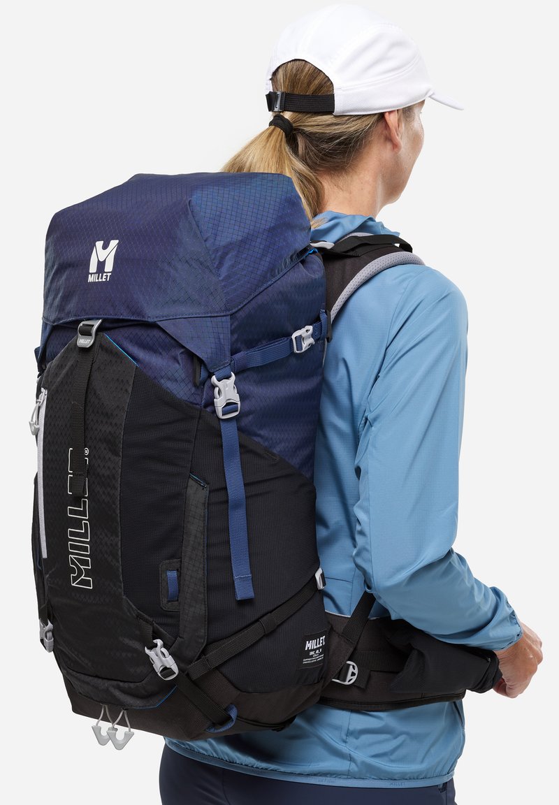 Sac à dos au design bleu et noir, fabriqué en tissu durable. Dispose de bretelles réglables, d'un détail de logo et de plusieurs points d'attache.