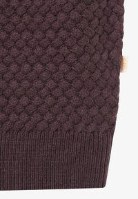 Geflochtener, dunkelvioletter Strickstoff mit texturiertem Muster, ausgestattet mit einem gerippten unteren Rand und einem kleinen Markenetikett an der Seite.