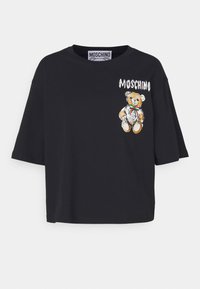 Černé oversized tričko s grafikou medvídka s zelenou a červenou stuhou. Název značky "Moschino" tištěn nad designem.