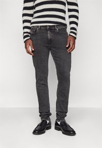 Svarta slim-fit jeans med en subtil blekning, denimtextur och standard femficksdesign. Bärs med svarta läderskor och en randig tröja.