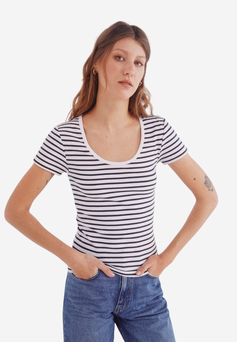 Gestreept T-shirt met korte mouwen en een ronde hals, met marineblauwe en witte horizontale strepen, ribbelstructuur, gedragen met hoge taille jeans.