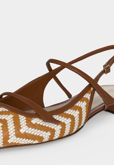 Καφέ και άσπρο πλεκτό επίπεδο σανδάλι με μυτερή μύτη και λεπτά διασταυρούμενα δερμάτινα λουράκια και ρυθμιζόμενο κούμπωμα με αγκράφα.