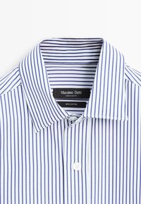 Hvid skjorte med blå lodrette striber, spredt krave og hvide knapper, mærket Massimo Dutti, lavet i Egypten, 100% bomuld.