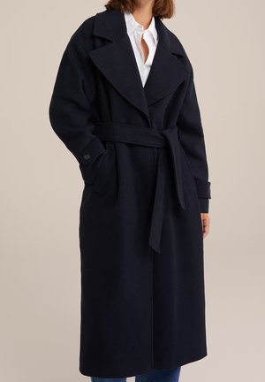 Marineblå uldblandet frakke med bælte i taljen, oversize krave og knaplukning ved ærmerne. Har en lige silhuet og er knælængde.