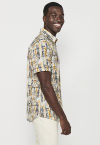 Korte mouwen shirt met een textuurpatroon in geel, blauw en wit, met een kraag en een rechte zoom.