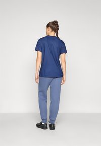 Mørkeblå teksturert t-skjorte med korte ermer, sammen med lyseblå joggebukser. Outfitten inkluderer svarte treningssko.