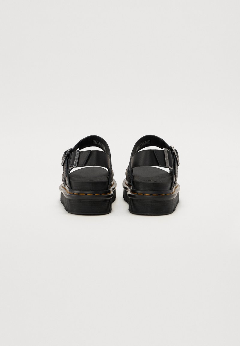 Schwarze Sandalen mit einer dicken Sohle, Schnallen-Detail und offenem Rückendesign. Obermaterial aus glattem Leder mit kontrastierendem Stich entlang der Sohle.