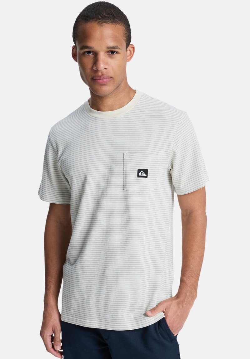 Camiseta de manga corta a rayas en tonos beige claro y azul, con cuello redondo y un bolsillo en el pecho con un parche de logo negro.