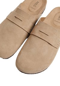 Beige suede instap schoenen met een platte zool, met een band over de bovenkant en uitsneden, en een gladde binnenvoering.