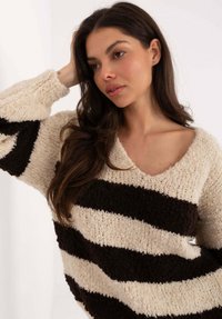 Grober Strickpullover mit cremefarbenen und dunkelbraunen horizontalen Streifen. V-Ausschnitt, strukturierter Stoff, lockere Passform und weite Ärmel.