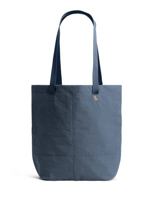 Blue tote bag with long handles, front pocket, and small embroidered owl logo on plain white background.