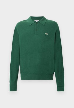Groene gebreide polo trui met kraag, drie knopen en Lacoste-logo. Heeft geribbelde mouwen en onderkant voor een getailleerde look.