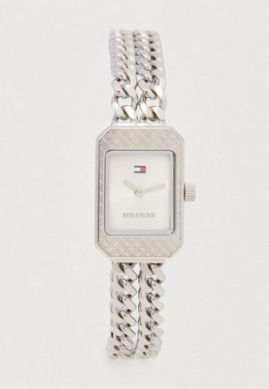 Zilveren rechthoekig horloge met gestructureerde metalen kast, witte wijzerplaat en schakelarmband. Beschikt over een klein logo en eenvoudige uurmarkeringen.