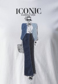 Witte T-shirt met een grafische illustratie van een figuur in een blauwe en donkere denim outfit, met de tekst "ICONIC mademoiselle" erboven.