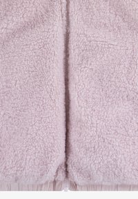 Pink fleece jacket with a textured, fluffy surface. Features a central zipper and elastic hem at the bottom for a snug fit. Soft and cozy material.