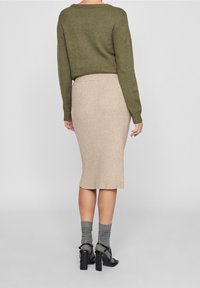 Olivgrön kortärmad tröja, beige ribbad midikjol, grå strumpor och svarta klacksandaler, sedd från baksidan. Slät textur, figurnära design.