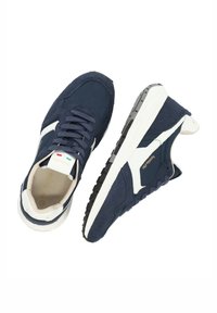 Zapatillas azul marino hechas de ante y malla con acentos blancos, puntera redonda, suela plana de goma y cordones en la parte delantera. Diseño simplista con marca.