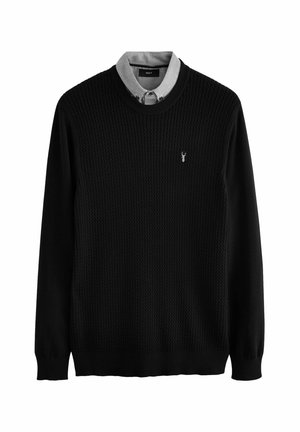 Black knitted sweater with a textured design, featuring a gray collared shirt underneath. Small logo accent on the chest.